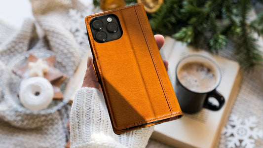 closeup photo of iPhone 16 Pro Max leather wallet case held in woman's hand with white sweater and cozy background