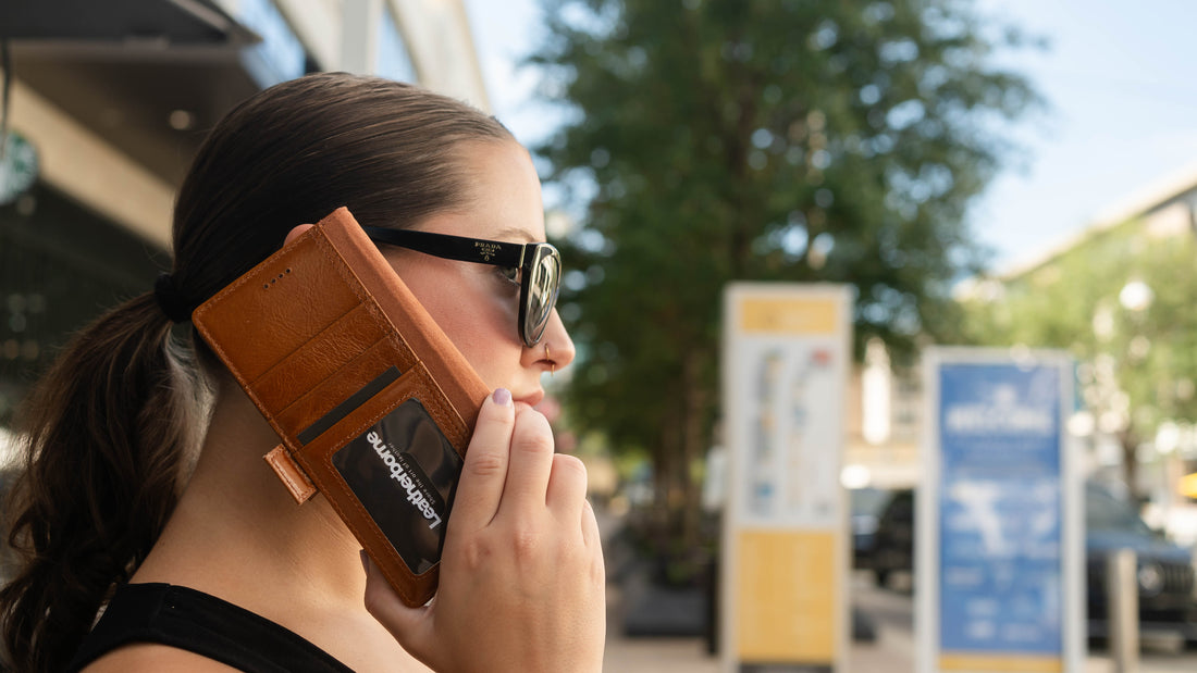 woman in black sunglasses using brown leather wallet case outside