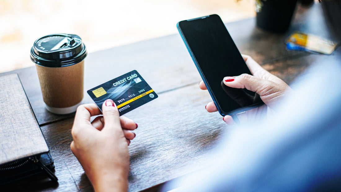 woman hands with red nails holding phone and credit card, coffee and wallet on the side