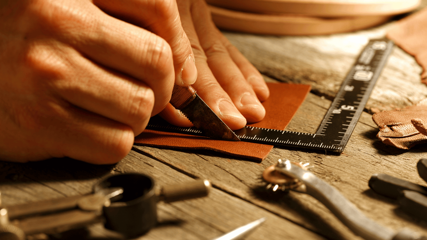 Leather being cut with a sharp tool to create a phone case.