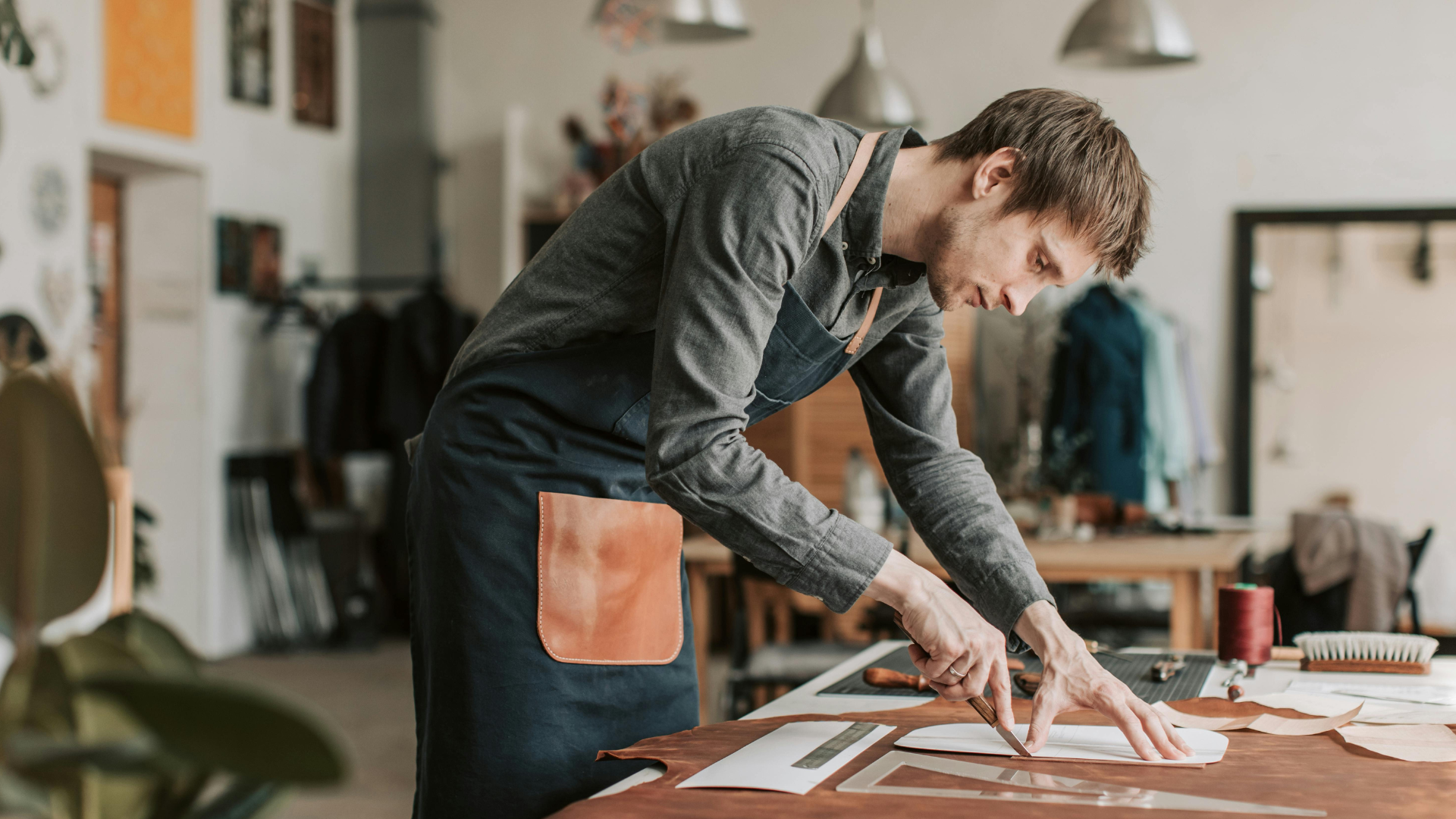 A leather artist cutting premium full-grain leather to create a phone case.