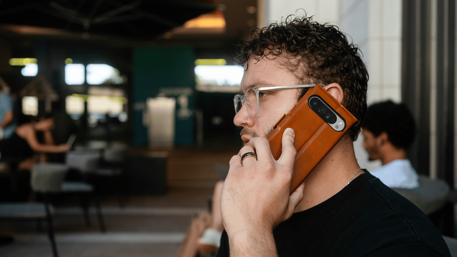A young man making a call with his phone in a Google Pixel 9 Pro XL leather wallet case.​⬤